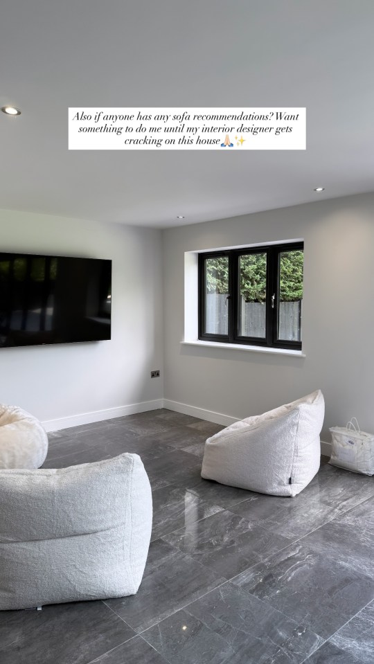 Interior of a room with white beanbag chairs, a large TV, and dark gray floor tiles.
