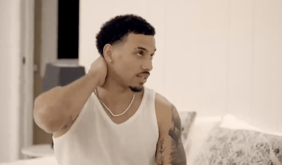 Man in a white tank top looking pensive.