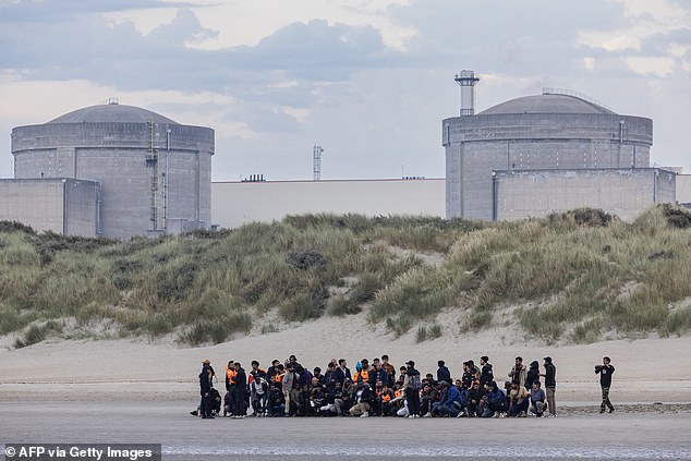 The migrants waited in a group on the beach - apparently under instruction from smugglers