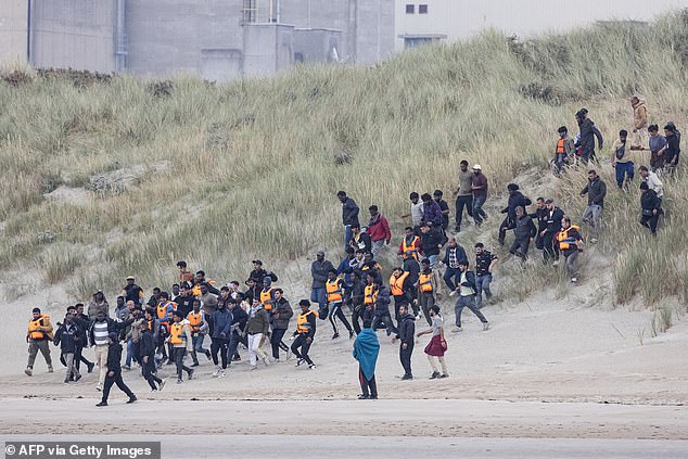 Migrants running down the sand dunes onto the beach at Gravelines in northern France