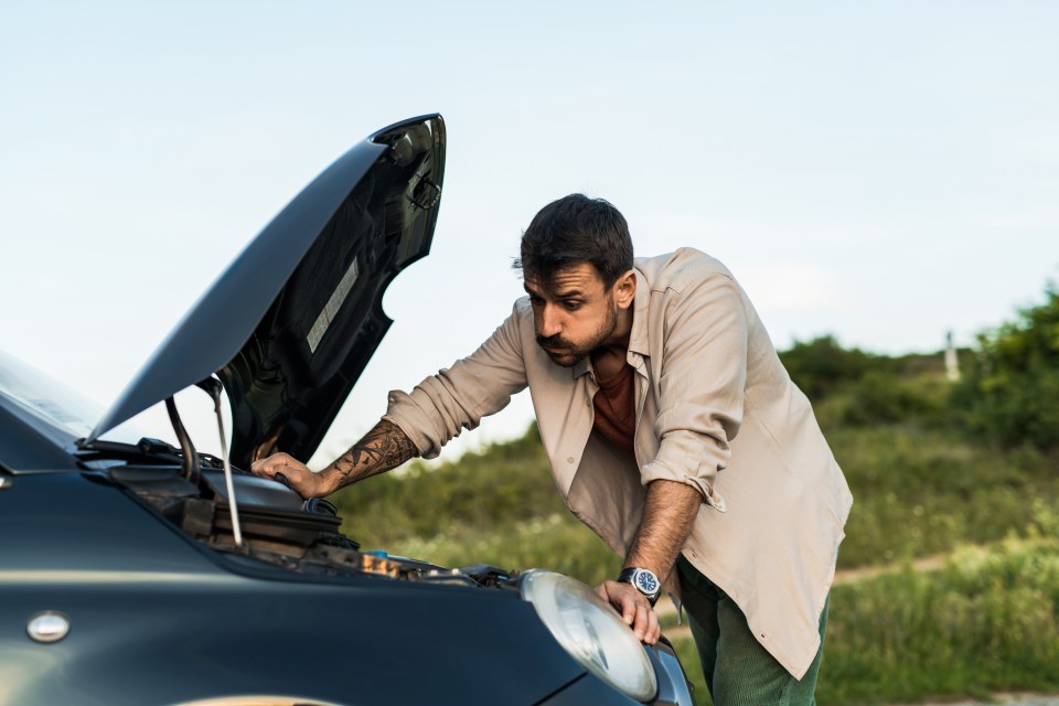 Man examining his broken-down car.