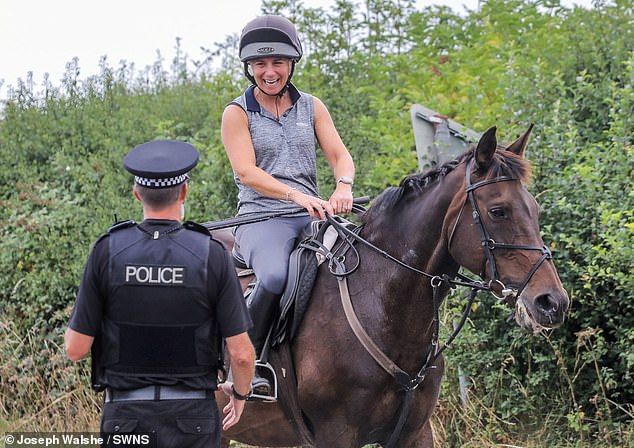 Roads, footpaths and village lanes in and out of the hamlet of Dean have been sealed off and locals are being questioned by police and security (Pictured: a woman on horseback talking to a police officer)