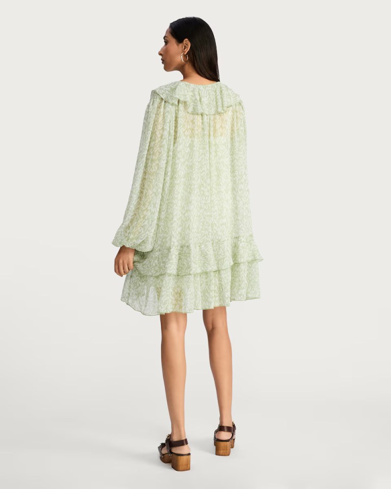 Model wearing a light green patterned dress from the back.