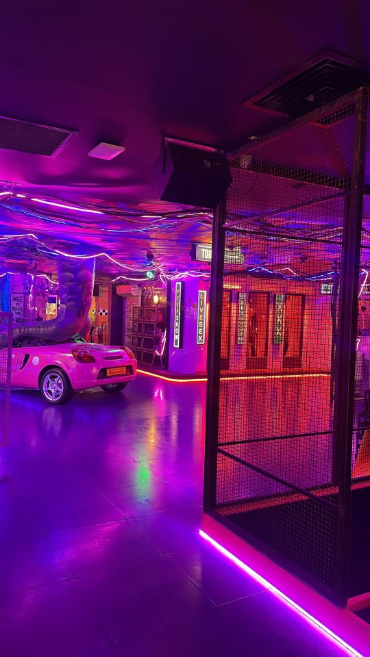 Pink car in a neon-lit room.