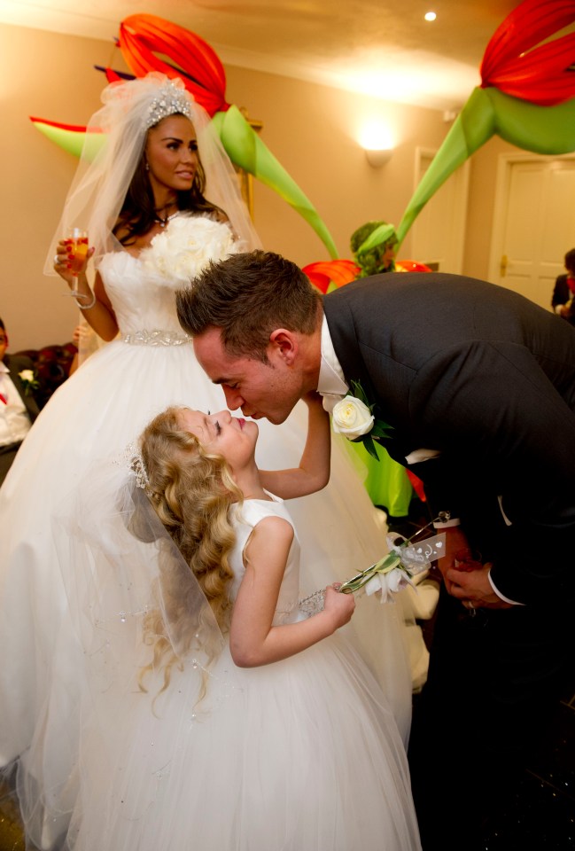 Groom kissing a young flower girl at a wedding.