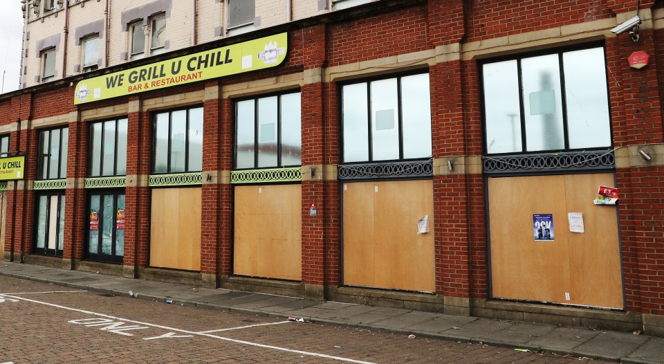 Boarded-up storefront of a bar and restaurant.