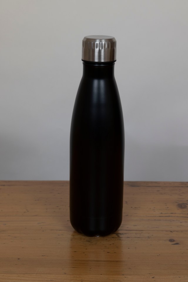 Black insulated water bottle on a wooden table.