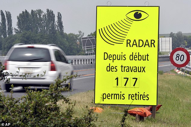 A vehicle passes in front of a sign of the Vaud Cantonal Police indicating the number of driving licences withdrawn for speeding in the construction zone on the A1 motorway between Lausanne and Yverdon, Switzerland