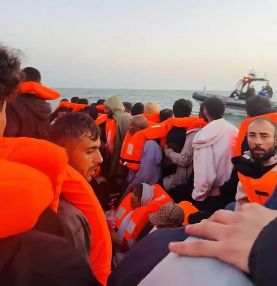 Migrants in life vests on a small boat at sea.