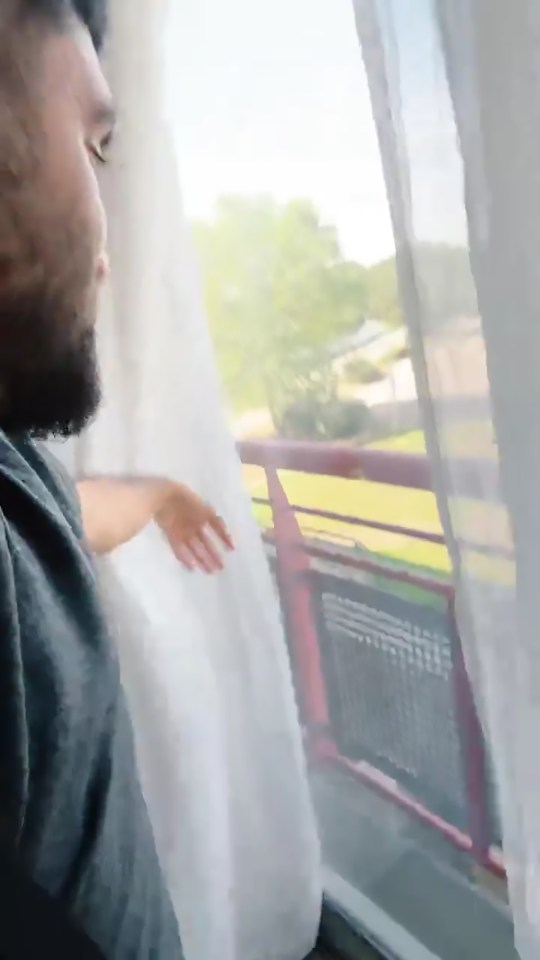 Man opening curtains to look outside from a balcony.