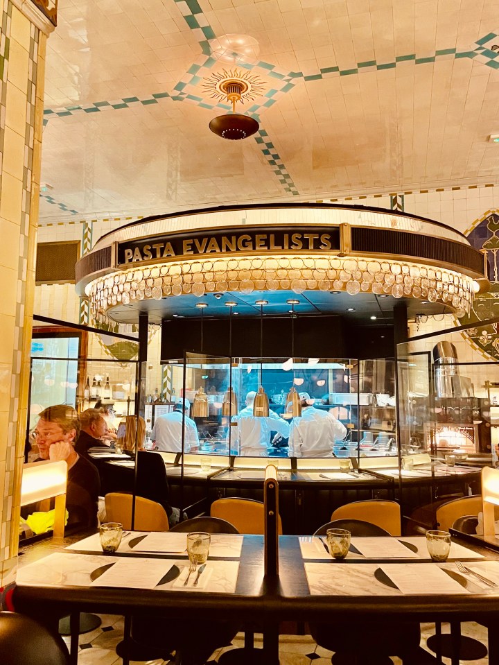 Interior view of Pasta Evangelists restaurant, showing the open kitchen and dining area.