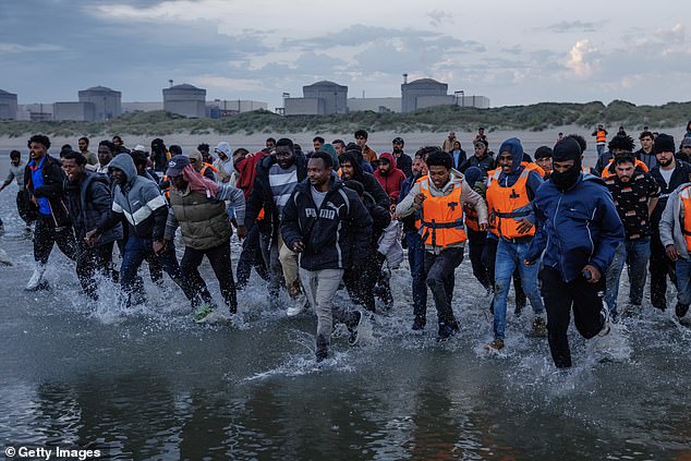 Migrants wade into the sea in an attempt to board a small boat on August 12, 2025 in Gravelines