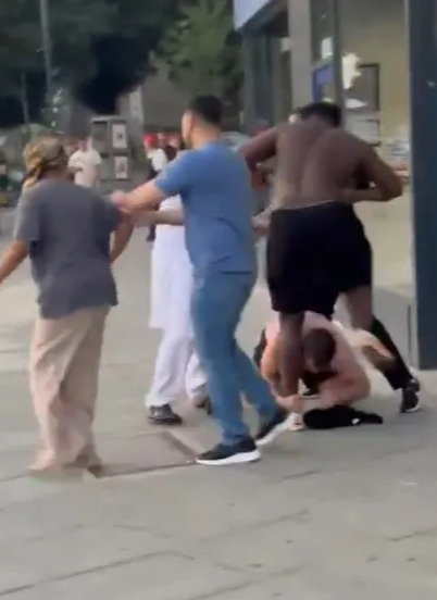 People fighting on a city street.
