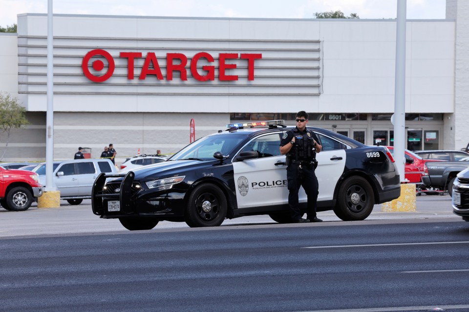 Police officer standing by police car outside Target store.