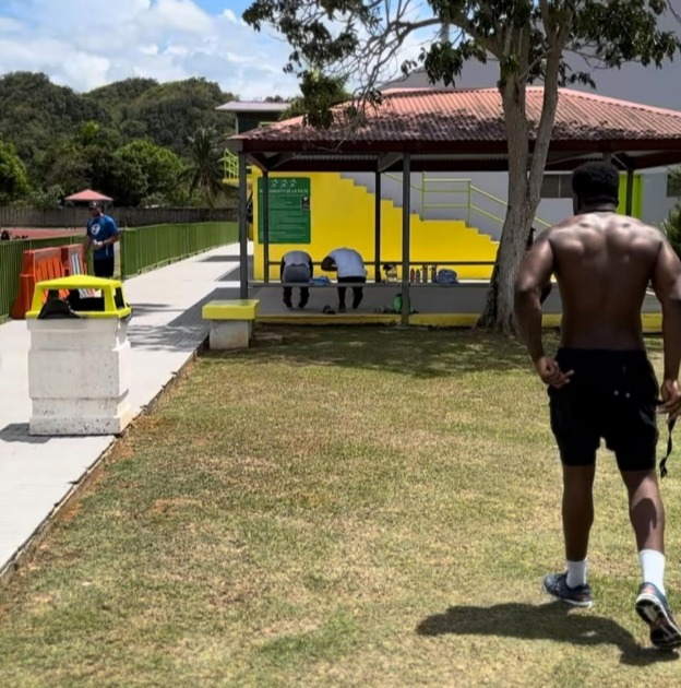 Man walking past people exercising in an outdoor pavilion.