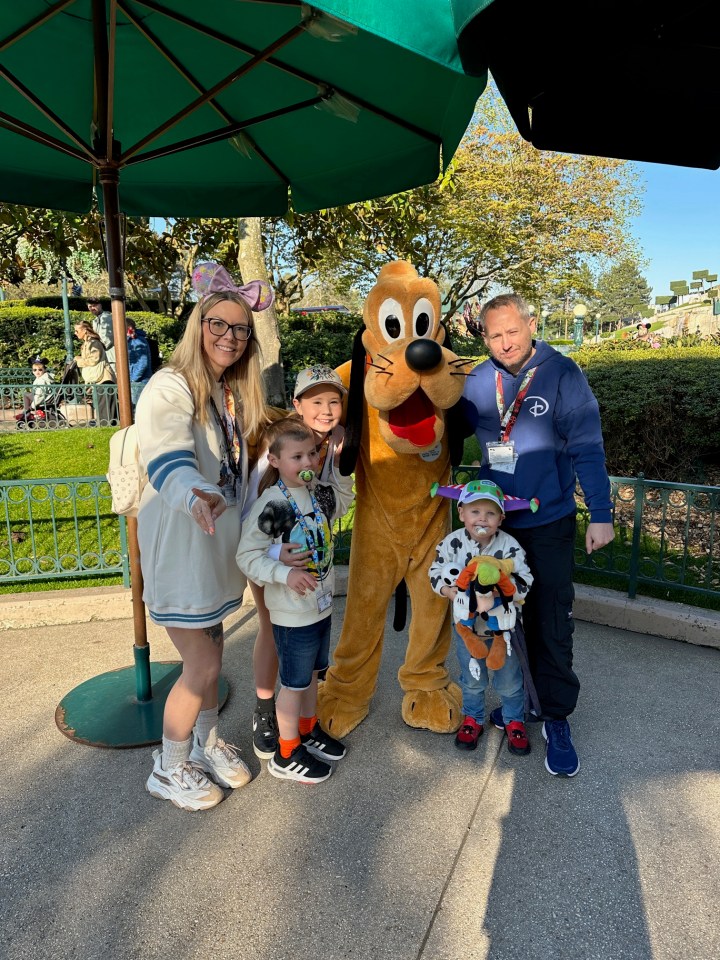 Family posing with Pluto at a theme park.
