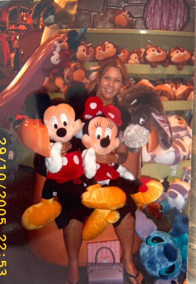 Woman holding large Mickey and Minnie Mouse plush toys.