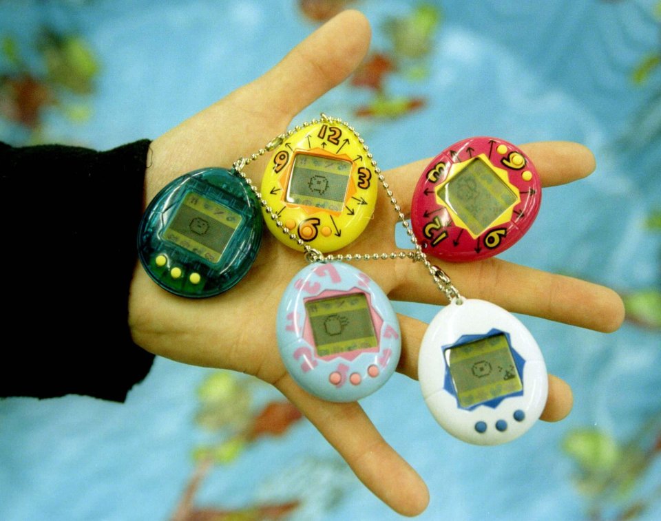 Woman holding up a pink Tamagotchi.