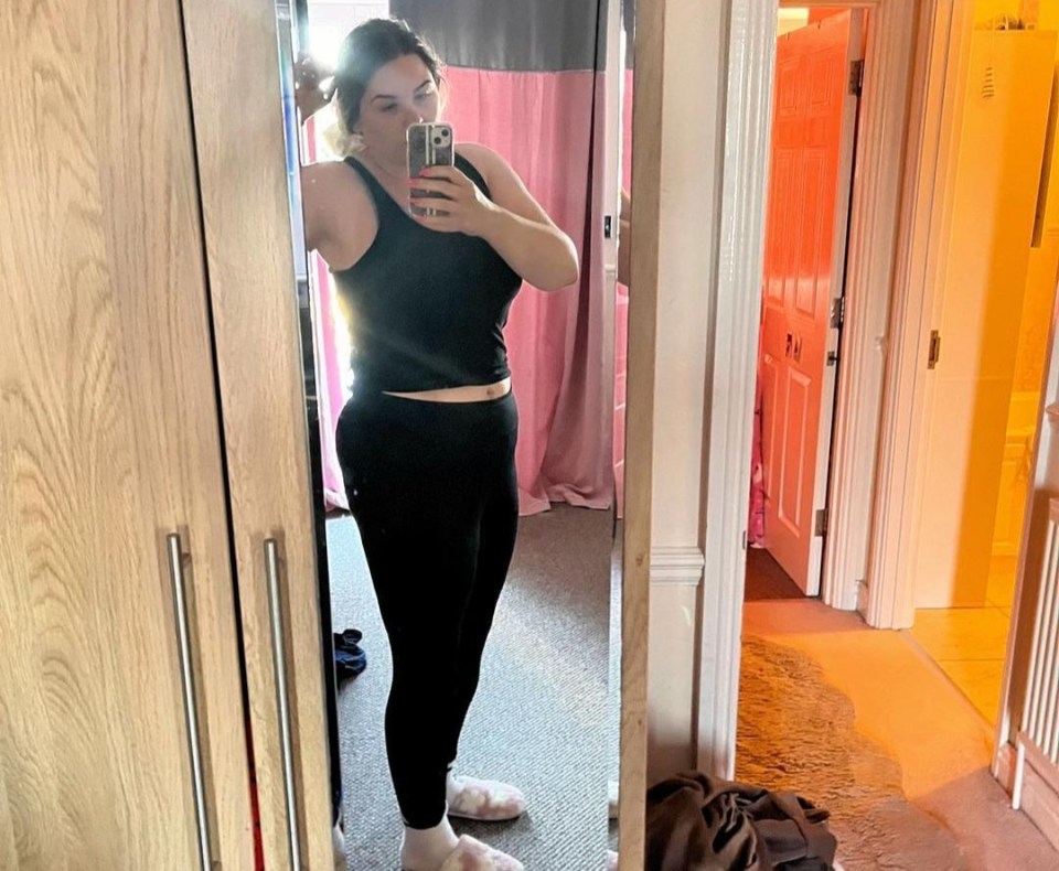 Woman taking a selfie in a mirror, showing her weight loss progress.
