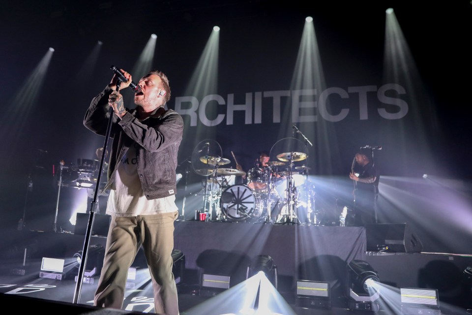 Sam Carter of Architects performing on stage.