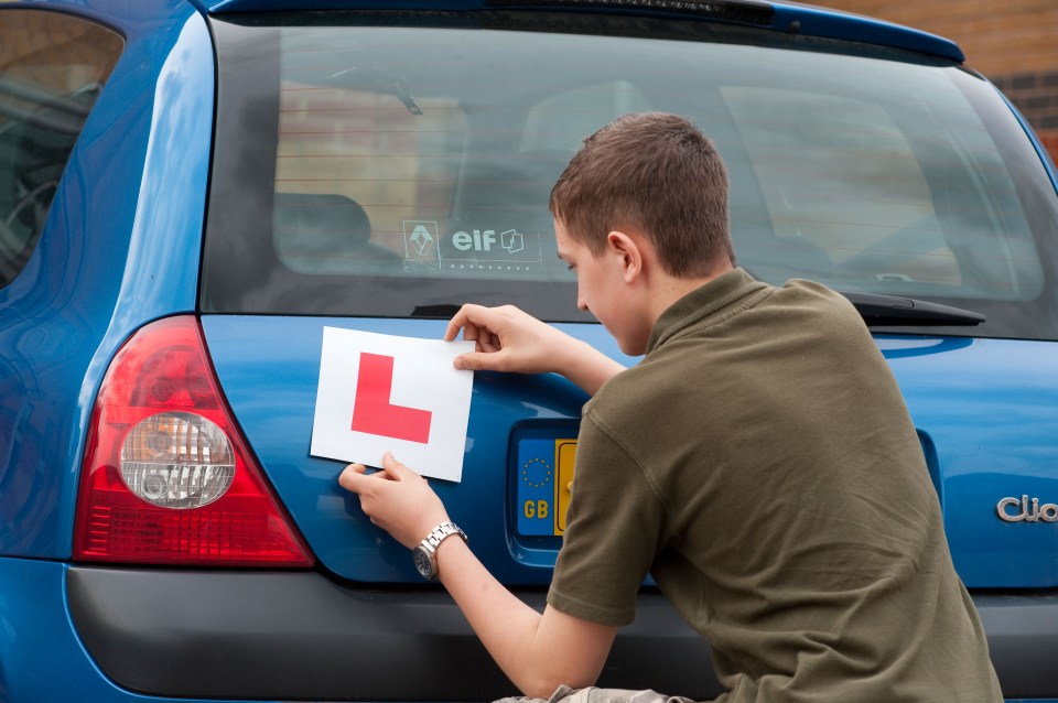 Teenage boy attaching an L-plate to a car.