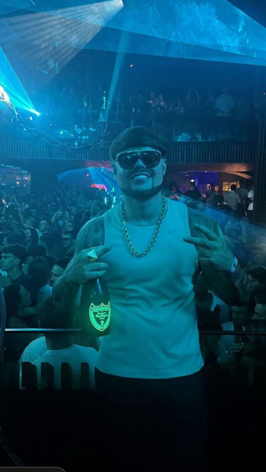 Jack Kay at a nightclub in Ibiza holding a bottle of champagne.