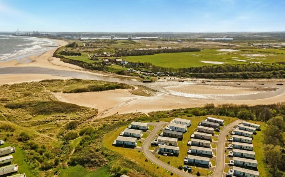 Aerial view of Sandy Bay, Northumberland, showing a caravan park and coastline.