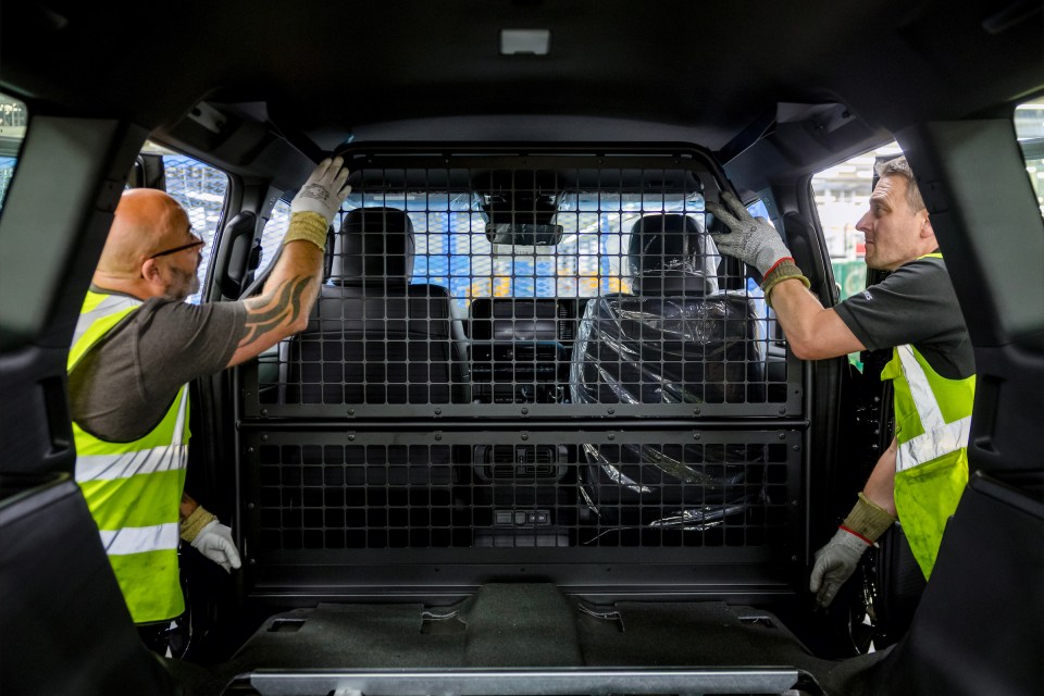 Two workers installing a partition in the back of a vehicle.