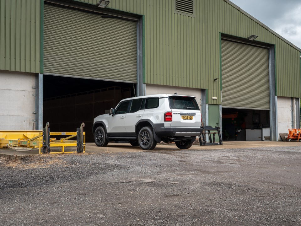 White Land Cruiser parked outside a barn.