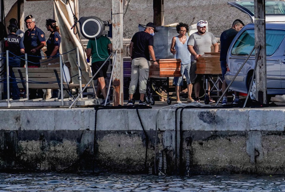 Coffins being moved at a dock following a migrant shipwreck.