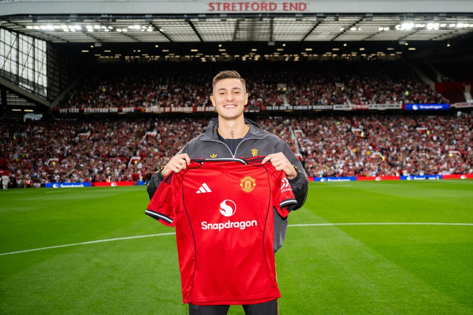 Benjamin Sesko holding a Manchester United jersey at Old Trafford.