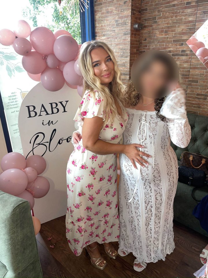 Two women at a baby shower; one in a floral dress, the other in a white lace dress.