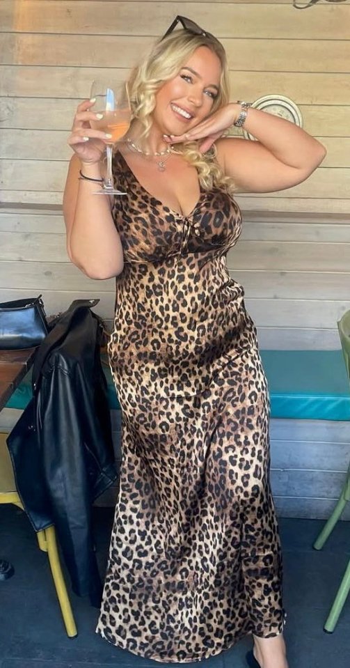 Woman in leopard-print dress holding a drink.