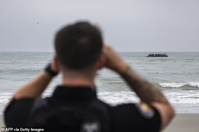 Watching on: A French gendarme watches the boat with a pair of binoculars