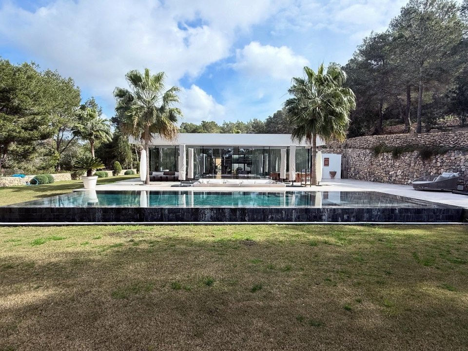 Modern house with infinity pool and palm trees.