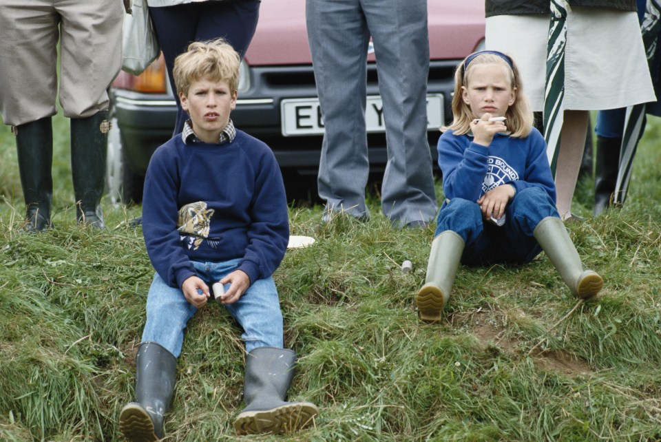 Peter and Zara Phillips as children sitting in the grass.