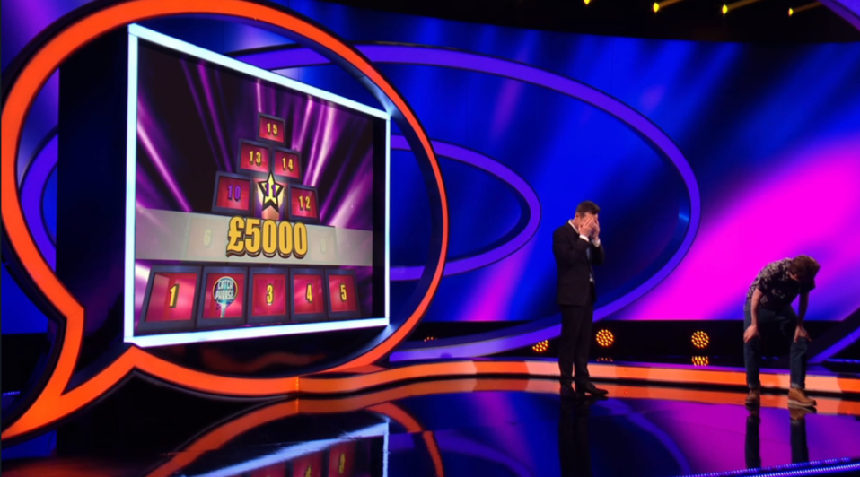 Screenshot of Catchphrase game show: a contestant has just lost £5000, the host covers his face.