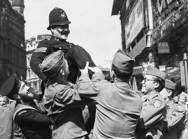 A policeman is held aloft by American military men in London on VJ Day, August 15, 1945