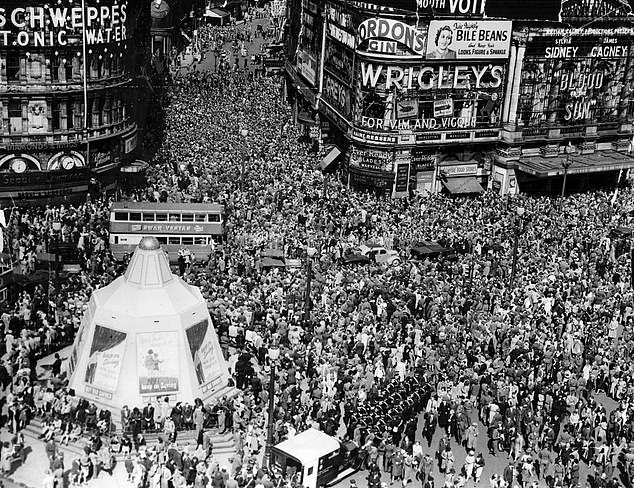 Crowds gathered in Piccadilly Circus and Shaftesbury Avenue with St. John Ambulance crews ready for an emergency in the foreground, August 15, 1945