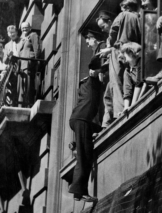 A sailor climbing into a window in Aldwych during VJ Day celebrations, August 10, 1945
