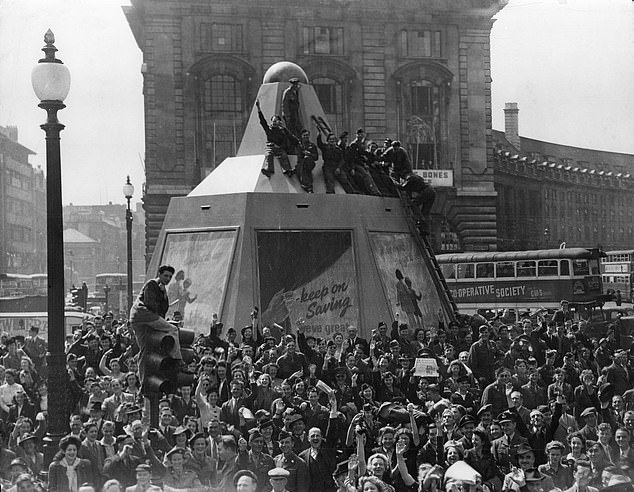 A cheering crowd at Piccadilly Circus on August 10, 1945, after news of Japan's imminent surrender emerged. One man has climbed the traffic lights