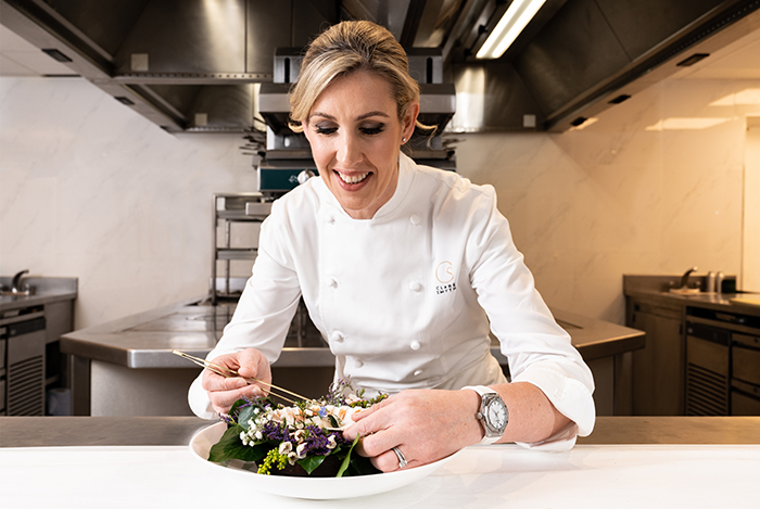 Clare Smyth plating a dish in a professional kitchen.