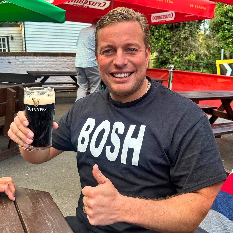 Man at pub holding Guinness, giving thumbs up.