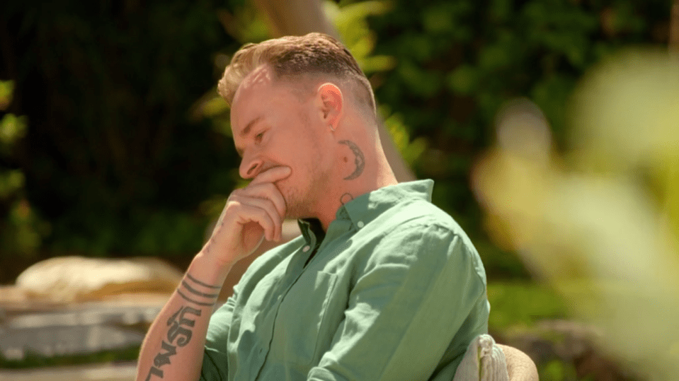 Man sitting outdoors, looking thoughtful.