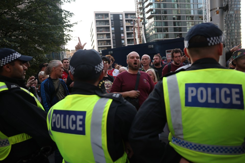 Police officers and counter-protesters outside a hotel.