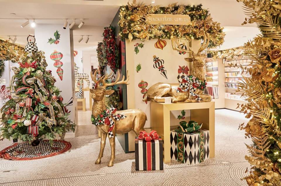 Harrods Christmas store display with gold deer statues, decorated Christmas tree, and gift boxes.