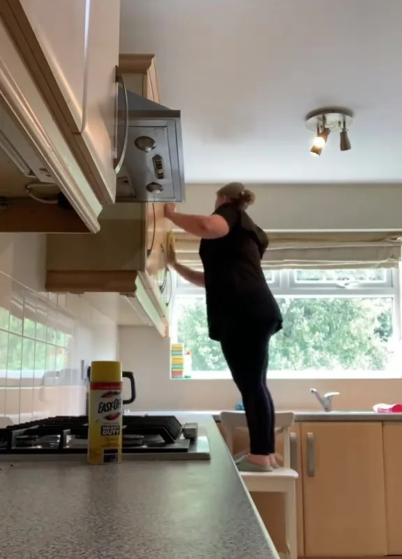 Woman cleaning kitchen cabinets.