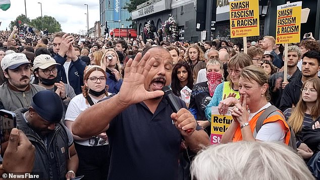 Wearing a black polo top and surrounded by cheering supporters, the councillor called protesters 'fascists' and drew his finger across his throat as he spoke to the crowd (pictured at the rally)