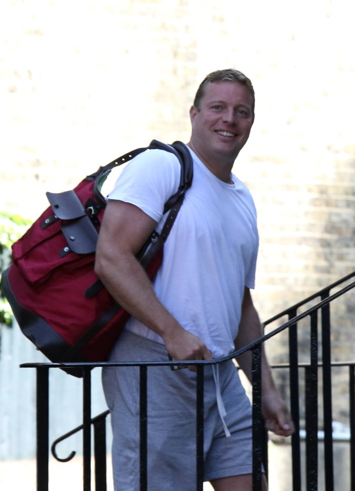 Man smiling while carrying a bag and walking down steps.