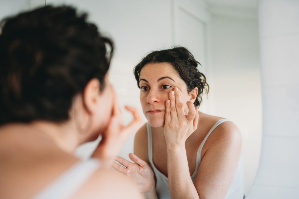 Woman examining her reflection in a mirror.